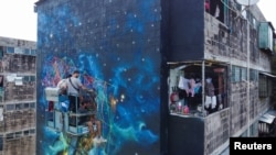 A drone view shows members of the Fullpaint 360 collective installing cords in a mural titled 