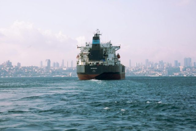 A large ship in the water with a city in the background