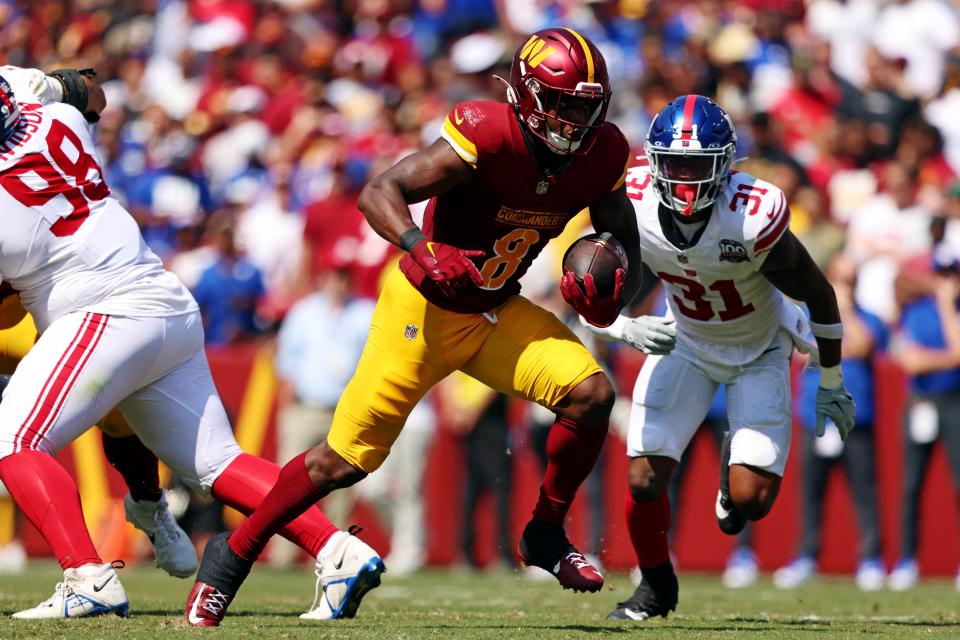 Sep 15, 2024; Landover, Maryland, USA; Washington Commanders running back Brian Robinson Jr. (8) runs the Balla against New York Giants safety Tyler Nubin (31) during the second quarter at Commanders Field. Mandatory Credit: Peter Casey-Imagn Images