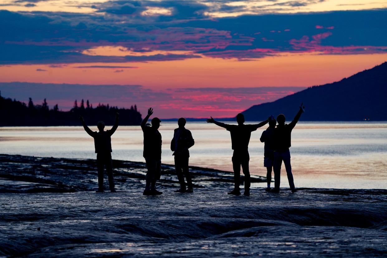Visitors to Hope, Alaska, wave hello as the sun briefly dips below the horizon on the summer solstice.
