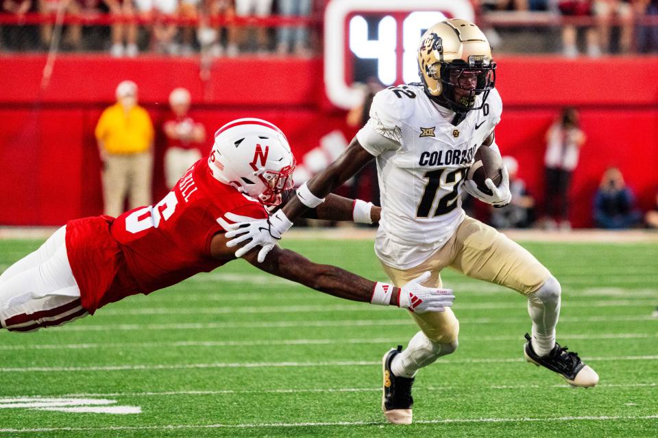 Sep 7, 2024; Lincoln, Nebraska, USA; Colorado Buffaloes wide receiver Travis Hunter (12) stiff arms Nebraska Cornhuskers defensive back Tommi Hill (6) during the second quarter at Memorial Stadium. Mandatory Credit: Dylan Widger-Imagn Images