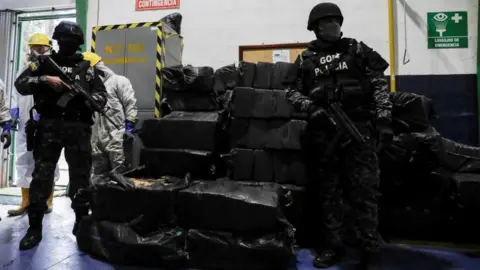 Reuters Police officers keep watch next to sacks containing cocaine packages before the incineration of more than nine tons of cocaine seized during different operations, according to the Ecuador's Interior Ministry, in a warehouse at an undisclosed location, in Ecuador April 21, 2022.