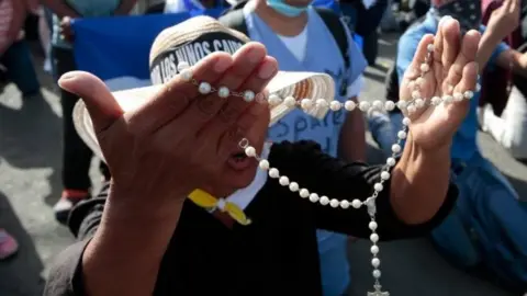 Reuters People pray in front of police that block the entrance of Divine Mercy Catholic Church in Managua, Nicaragua July 14, 2018