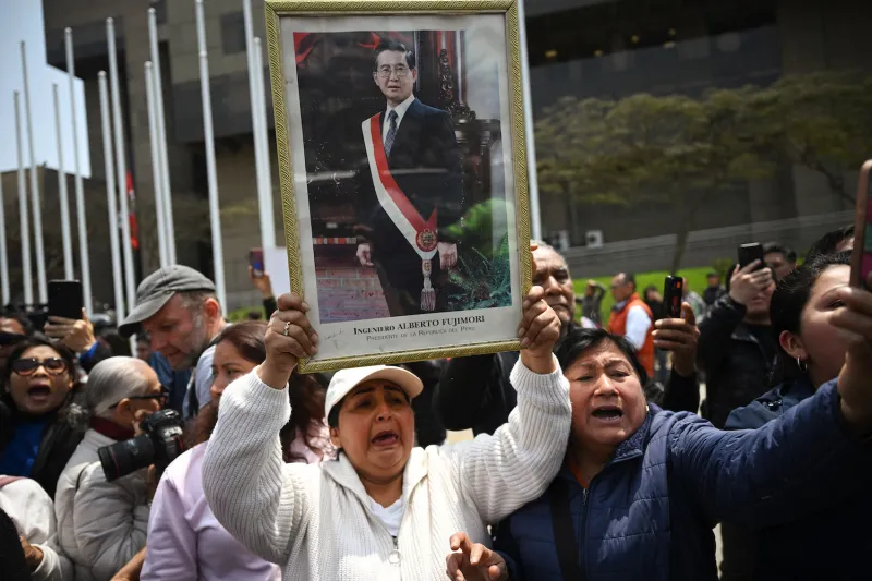 Supporters of late Peruvian President Alberto Fujimori wait for his hearse to pass in Lima on Sept. 12.