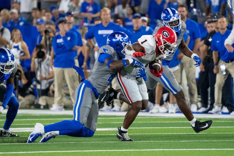 Sep 14, 2024; Lexington, Kentucky, USA; Kentucky Wildcats defensive back Kristian Story (4) tackles Georgia Bulldogs running back Trevor Etienne (1) during the third quarter at Kroger Field. Mandatory Credit: Tanner Pearson-Imagn Images