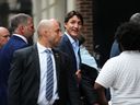 Prime Minister Justin Trudeau, flanked by entourage and security, smiles as he arrives to the CBS studios for the filming of The Late Show with Stephen Colbert in New York on Sept. 23, 2024.