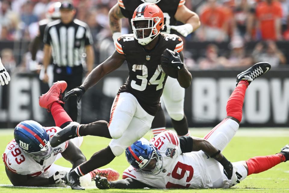 Sep 22, 2024; Cleveland, Ohio, USA; Cleveland Browns running back Jerome Ford (34) runs between New York Giants defensive tackle Rakeem Nunez-Roches (93) and linebacker Isaiah Simmons (19) during the second half at Huntington Bank Field. Mandatory Credit: Ken Blaze-Imagn Images