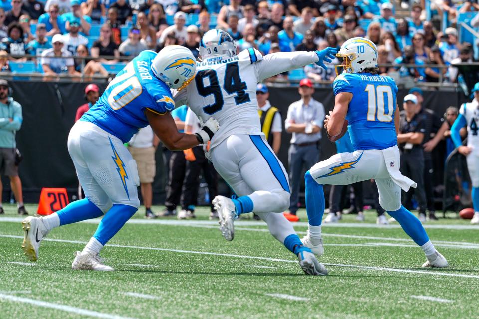 Sep 15, 2024; Charlotte, North Carolina, USA; Los Angeles Chargers quarterback Justin Herbert (10) drops back under pressure from Carolina Panthers defensive end A'Shawn Robinson (94) during the second quarter at Bank of America Stadium. Mandatory Credit: Jim Dedmon-Imagn Images