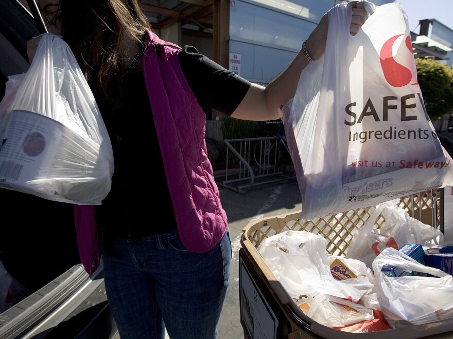 California will require shoppers to use paper bags or a reusable bag. In this photo from 2007, a woman loads plastic bags of groceries into her car at a Safeway store  in San Francisco, before the city — and later, the state — adopted a ban on plastic checkout bags.