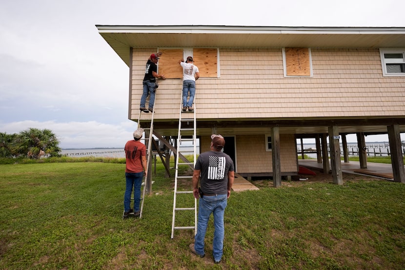 Jerry McCullen, top of ladder left, and Carson Baze, top of ladder right, put plywood over...