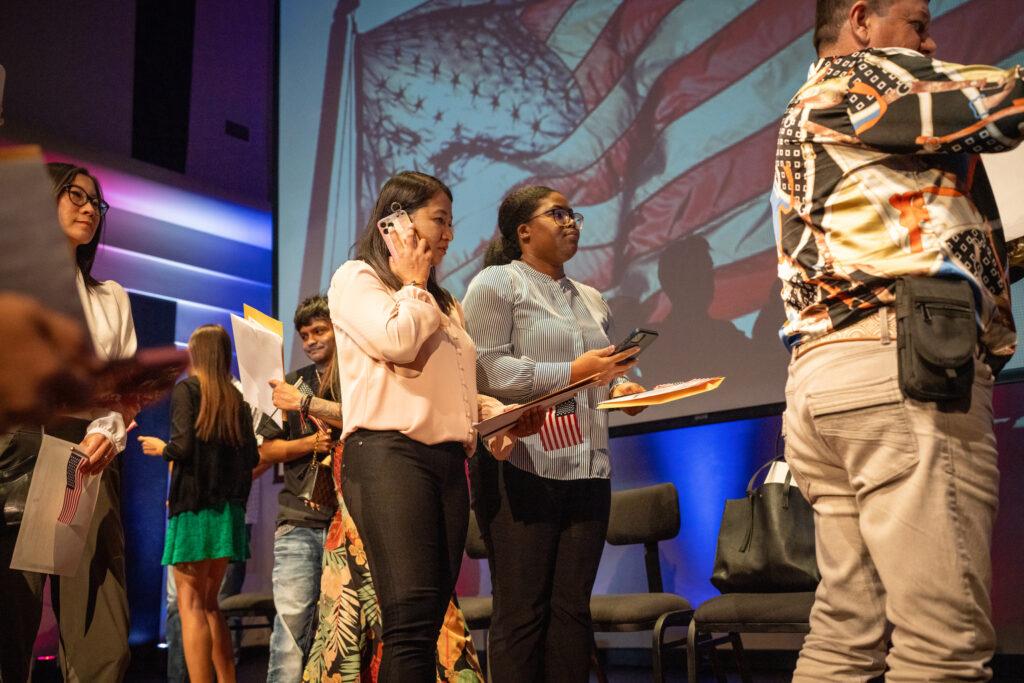 Stella Belony, of Haiti, in the striped shirt, is among new US citizens.