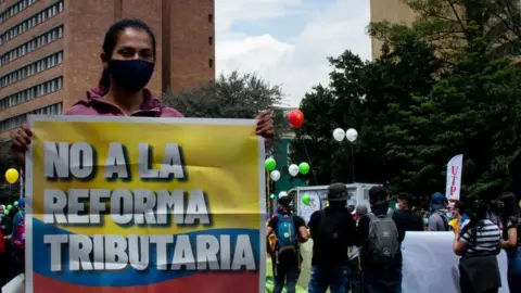 Getty Images A woman holds sign opposing the tax reform in Bogota, Colombia on April 28, 2021.