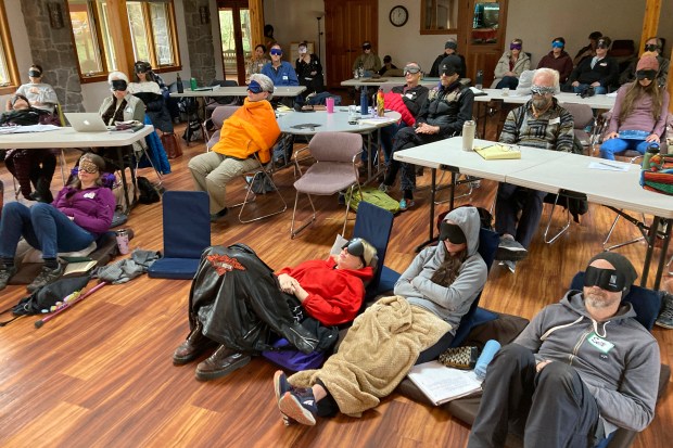 Psilocybin facilitator students sit with eye masks on while listening to music during an experiential activity at a training session near Damascus, Ore., on Dec. 2, 2022. They are being trained in how to accompany patients tripping on psilocybin as Oregon prepares to become the first state in America to offer controlled use of the psychedelic mushroom to the public. (AP Photo/Andrew Selsky)