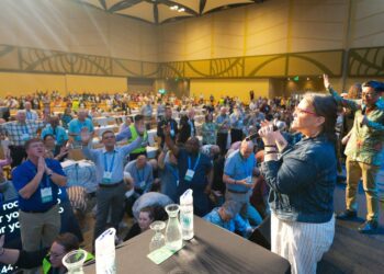 Worshipers in a conference meeting room sing and pray.