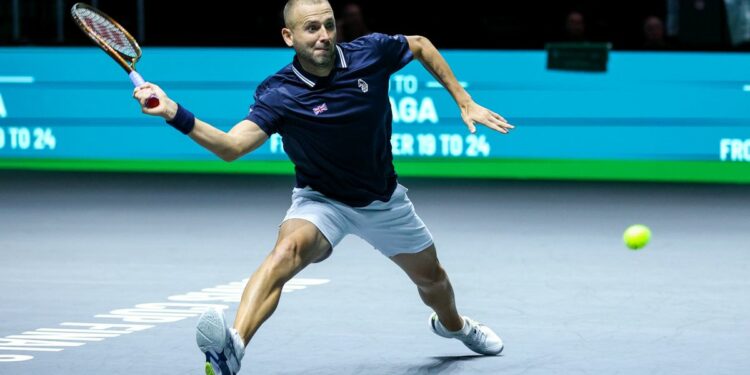 Dan Evans lunges for a forehand in the Davis Cup 2024, wearing a blue shirt and white shorts.