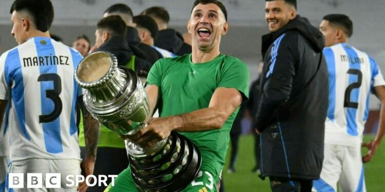 Argentina goalkeeper Emiliano Martinez holds a replica Copa America trophy against his crotch