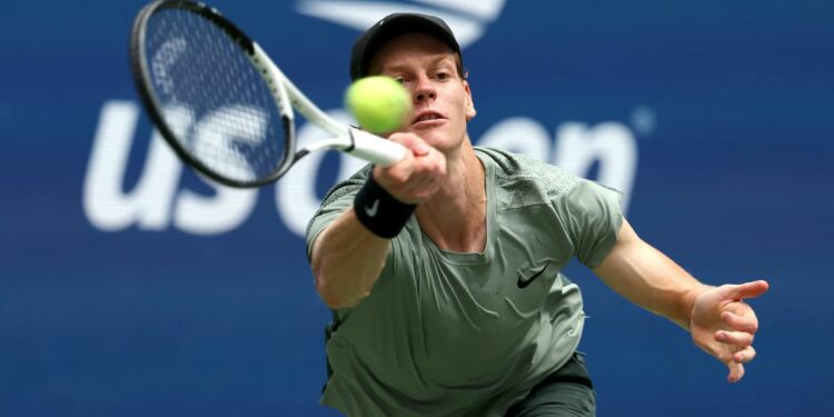 Jannik Sinner plays a forehand return at the US Open 2024 in a khaki t-shirt.