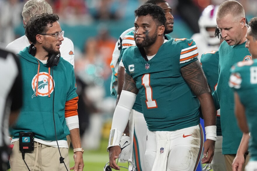 Miami Dolphins head coach Mike McDaniel talks to quarterback Tua Tagovailoa (1) as he leaves the game after suffering a concussion during the second half of an NFL football game against the Buffalo Bills on Sept. 12, 2024, in Miami Gardens, Fla.