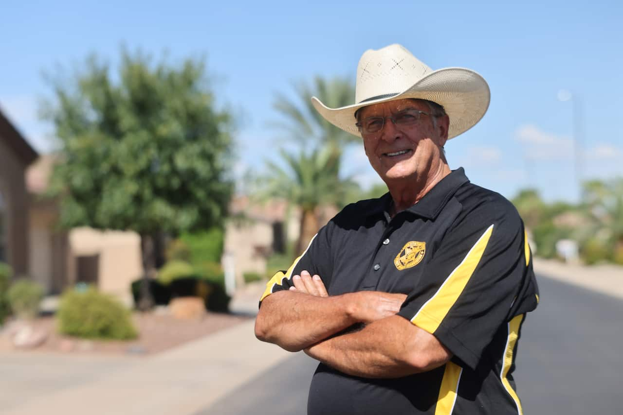 Former Graham County sheriff Richard Mack smiles with his arms folded, wearing glasses and a white cowboy hat. 