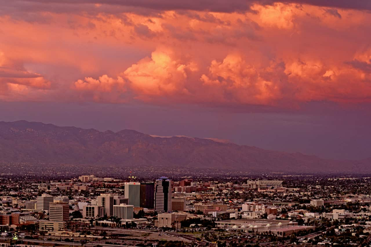 A view over a city at sunset, with mountains in the distance