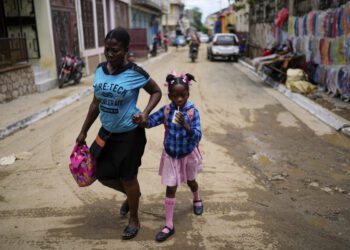 FILE - A child sips on a refreshment as she is walked home from school, in Cap-Haitien, Haiti, April 17, 2024.
