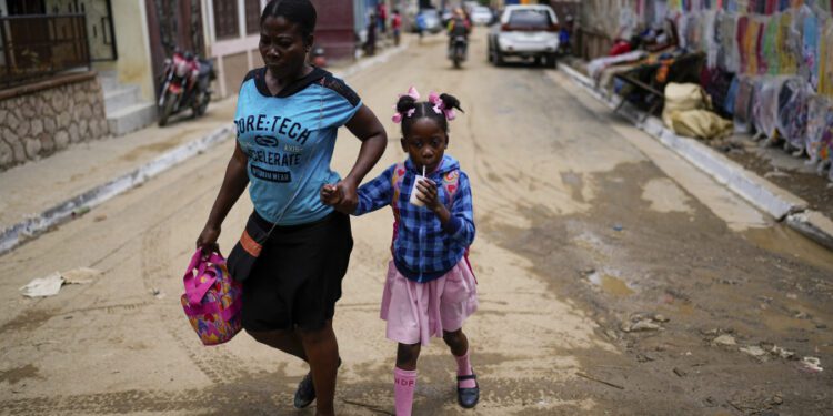 FILE - A child sips on a refreshment as she is walked home from school, in Cap-Haitien, Haiti, April 17, 2024.