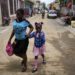 FILE - A child sips on a refreshment as she is walked home from school, in Cap-Haitien, Haiti, April 17, 2024.