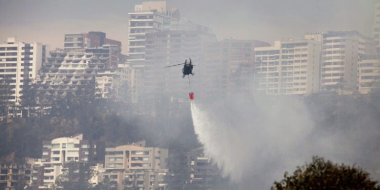 A helicopter sprays water over a bushfire on a hill in Quito on September 25, 2024 (Galo Paguay)