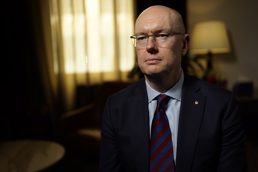 A man wearing a suit and tie and glasses.