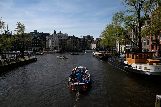 A boat cruises along a canal in Amsterdam, on April 12, 2024. (Photo by JOHN THYS / AFP) (Photo by JOHN THYS/AFP via Getty Images)