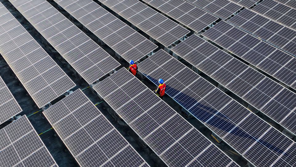 Workers inspect solar panels at a rooftop of a power plant in Fuzhou, in southern China's Fujian province in February. - AFP/Getty Images