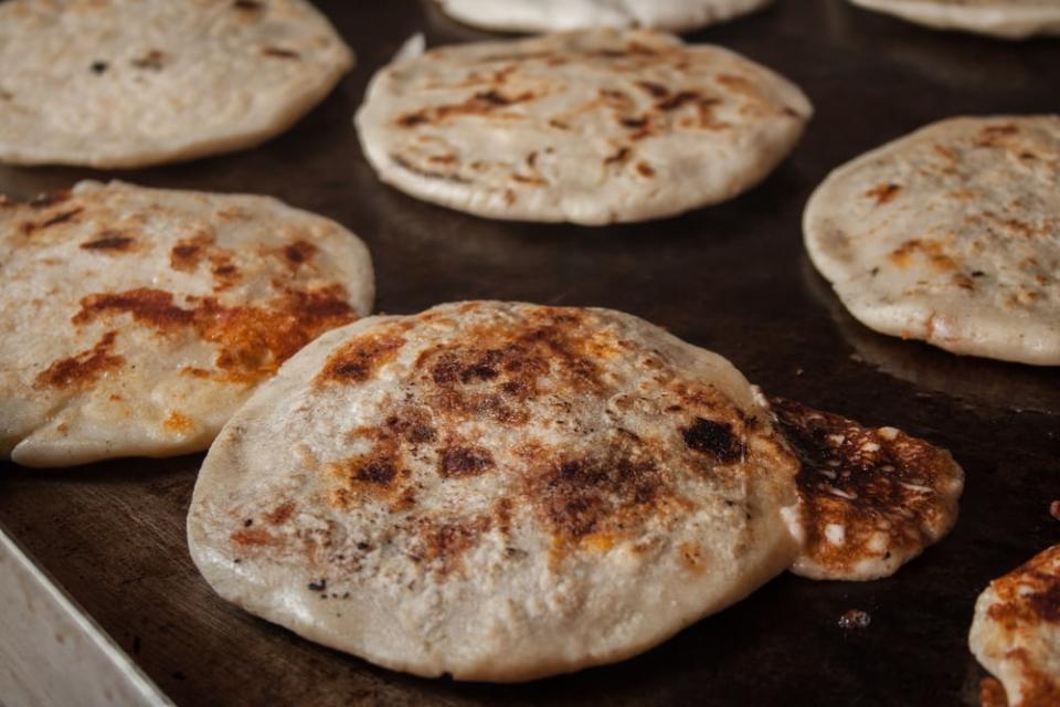 Pupusas, El Salvador's national dish, are traditionally made with corn flour and are stuffed with a variety of fillings like meat, cheese and beans.