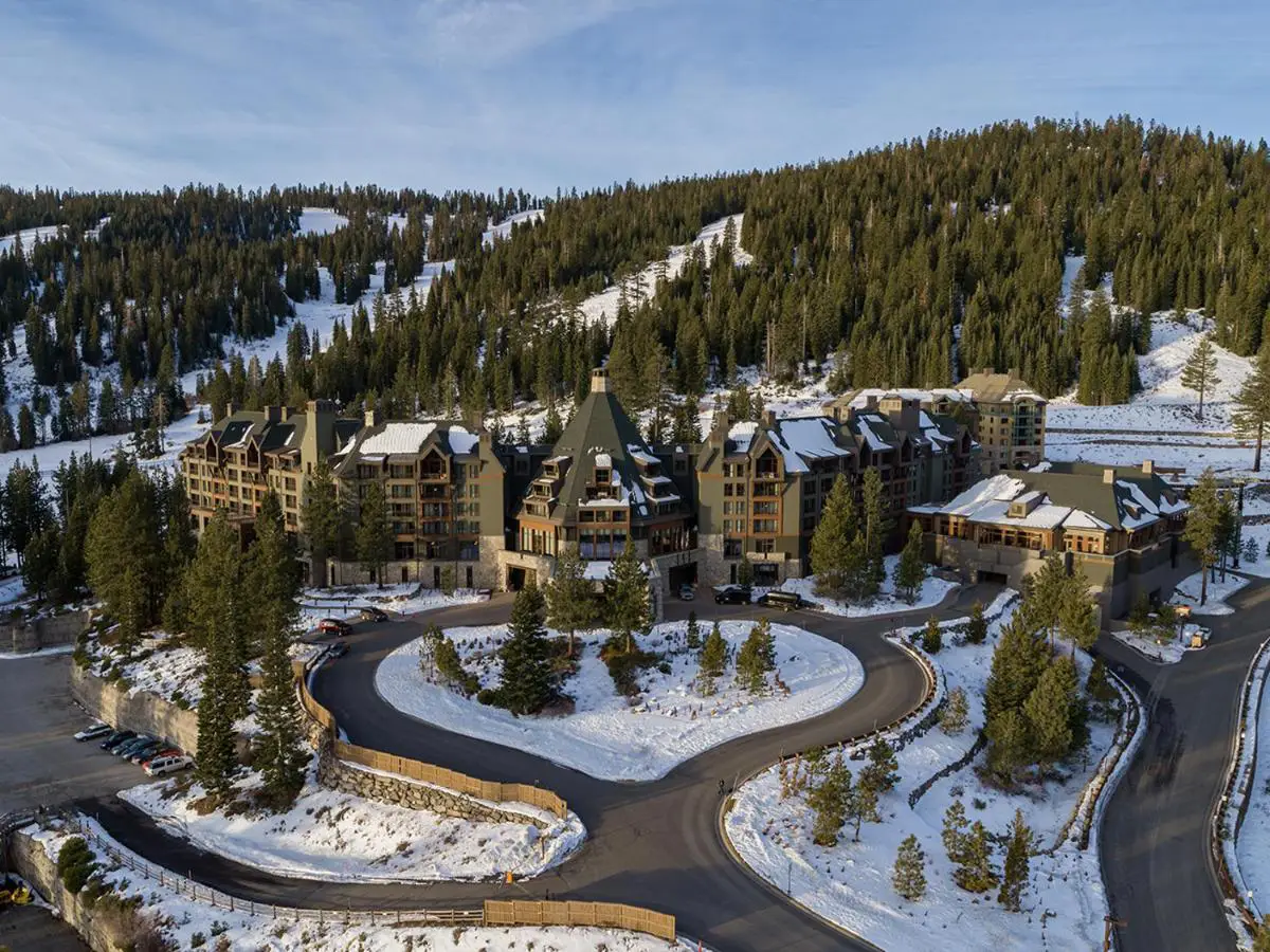 Aerial view of The Ritz-Carlton, Lake Tahoe surrounded by snow-covered mountains and evergreen trees.