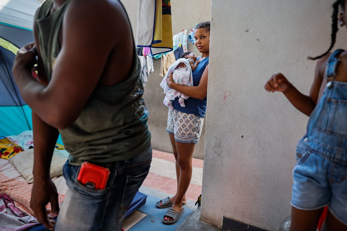 Haitian migrant Wilda Poulard held her 1-month-old baby, Ruthny Taika Saint-Vil Poulard, while watching her partner, Roby Saint-Vil (left), and 4-year-old-daughter, Analyssa Robyanca Saint-Vil, at a shelter in Mexico with hundreds of other migrants. The family planned to travel to Boston. 