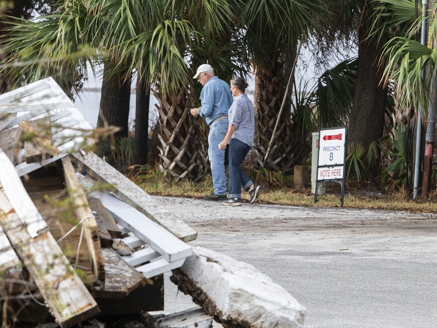 Voters walk through debris to vote in a new polling location after their regular polling place was damaged by Hurricane Michael in Wakulla Country, Fla., in November 2018.