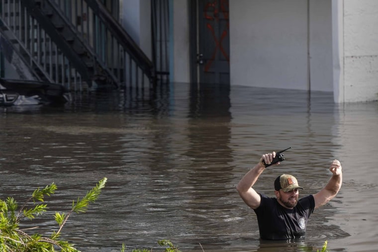 A water rescue team member walks through floodwaters