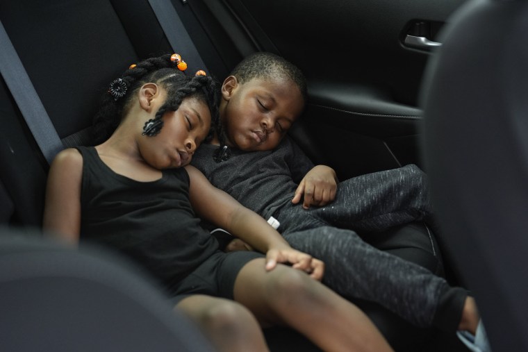 Siblings Saboria, 4, left, and Messiah Tyler, 3, nap in the backseat of a car after the roof was torn off their home in Palmetto, Fla., Thursday, Oct. 10, 2024.