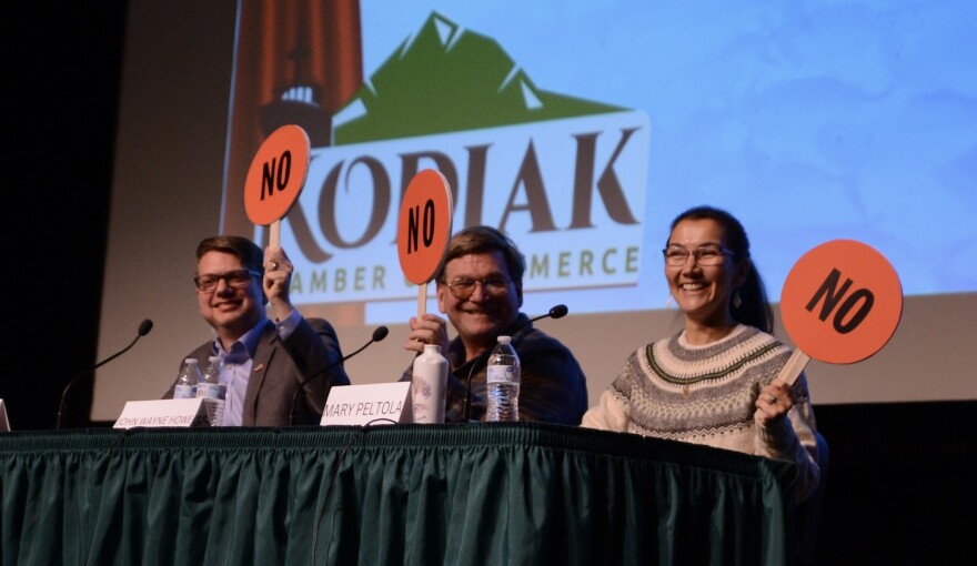 From left to right, Nick Begich III, Republican candidate for U.S. House; Alaskan Independence Party candidate John Wayne Howe; and Rep. Mary Peltola, D-Alaska, hold up paddles indicating their opposition to fish farming in Alaska. Howe had jokingly looked at Begich III's paddle before making a decision.