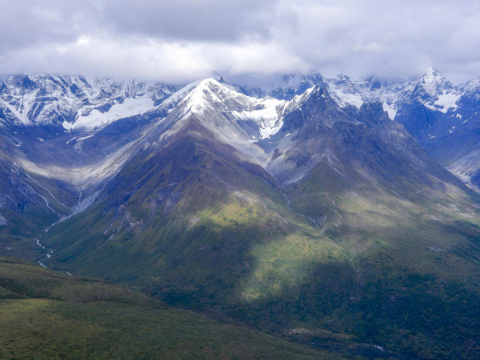 Awe-inspiring aerial view of snowcapped Wrangell Mountains dominating the rugged mountain scenery colored in various shades of green and hundreds of glaciers, ice fields and fast-moving streams, taken from a scenic flight prop plane, Wrangell-St. Elias National Park, Alaska, USA