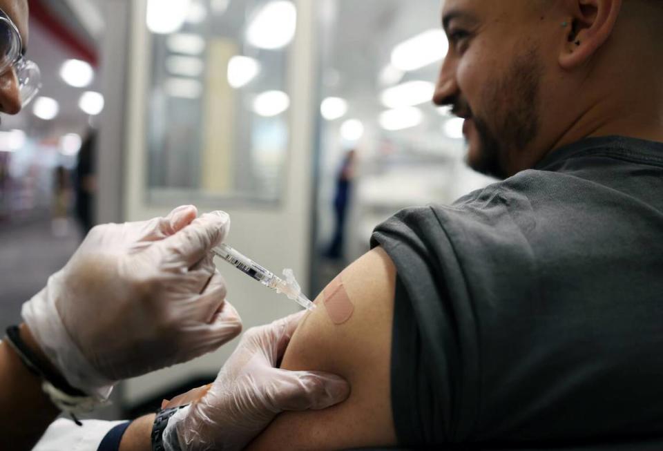 Brandon Guerrero, 34, of Compton, receives both a flu and COVID-19 vaccine at CVS in Huntington Park on Aug. 28, 2024.