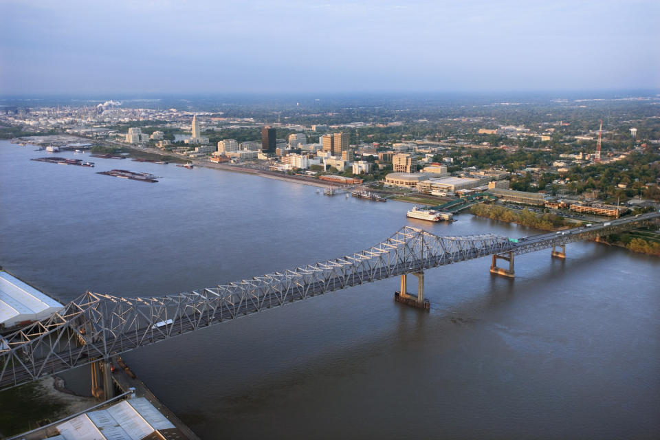 Aerial view of a bridge spanning a wide river with a cityscape in the background