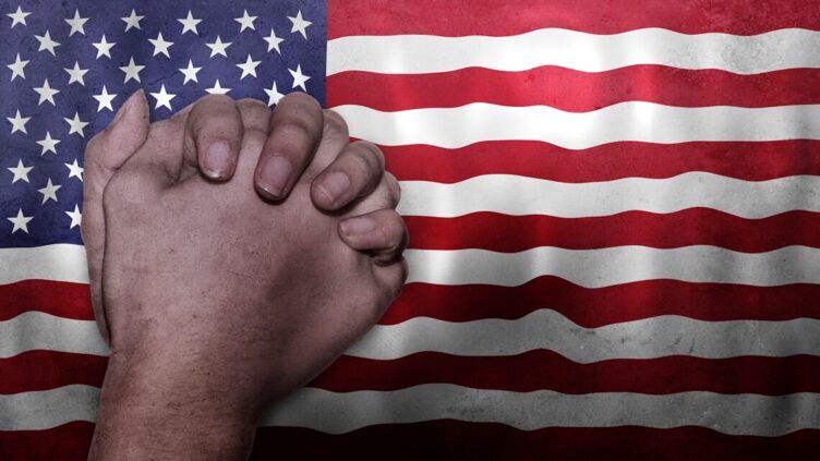 Praying hands and a U.S. flag