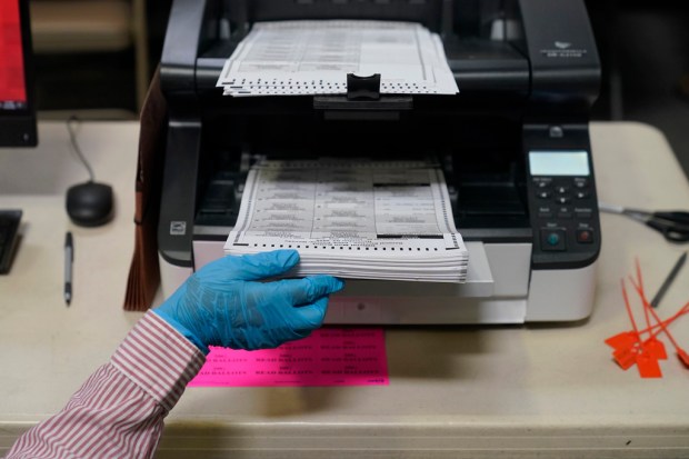 FILE – A county worker loads mail-in ballots into a...