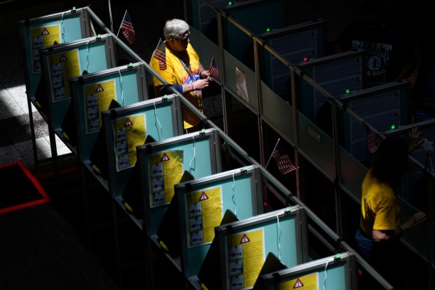 FILE – Poll workers help people vote in the Nevada...