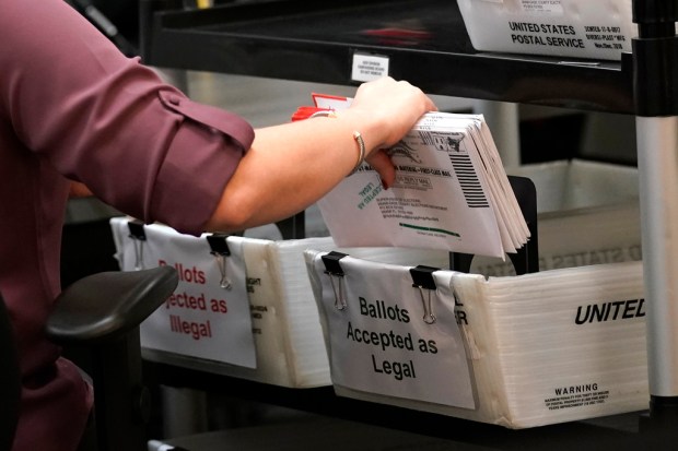 FILE – An election worker sorts vote-by-mail ballots at the...