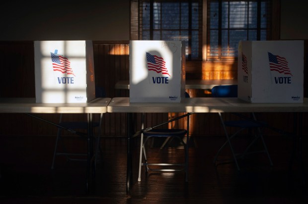 FILE – The shadow of a voter entering the precinct...