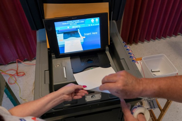 FILE – A polling judge, right, helps guide a voter’s...