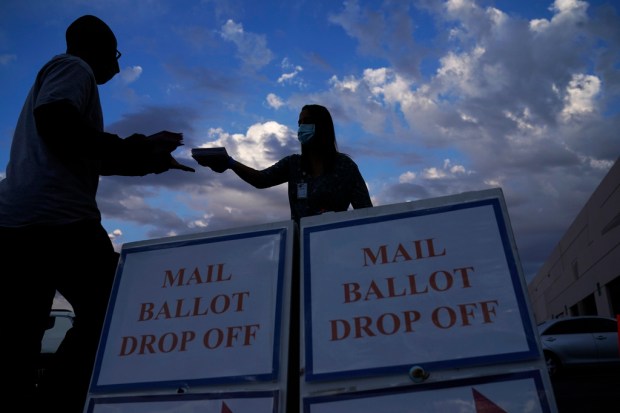 FILE – A county worker collects a mail-in ballots in...