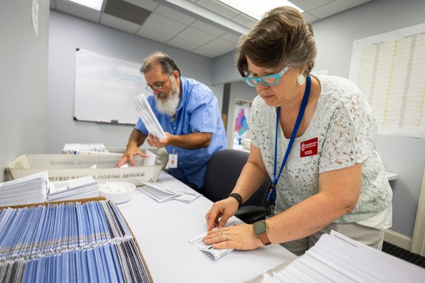 FILE – Dawn Stephens, right, and Duane Taylor prepare ballots...