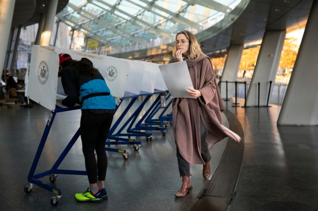 FILE – A voter moves to cast her ballot at...